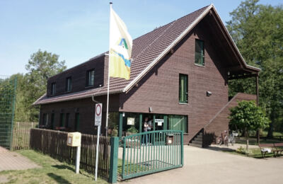 Dunkles Holzhaus der Jugendherberge Lübben mit Fahnenmast und Eingang zur Rezeption